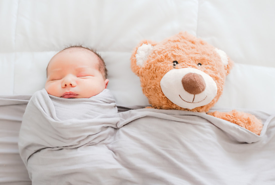 Newborn wrapped beside a teddy bear